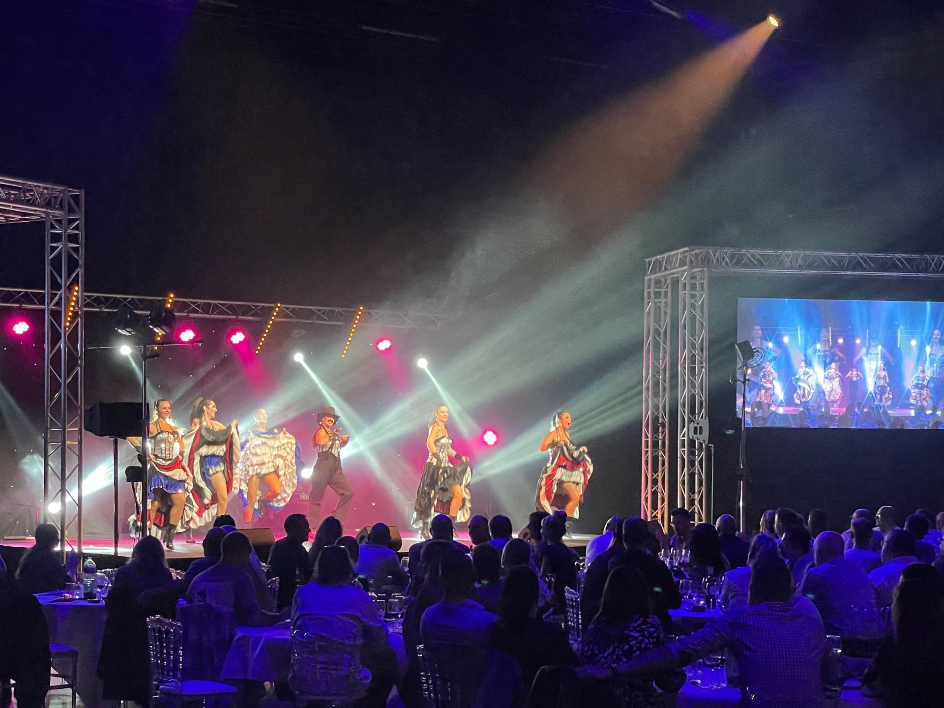 Spectacle de french cancan sur scène devant des écrans géants lors d'une soirée d'entreprise
