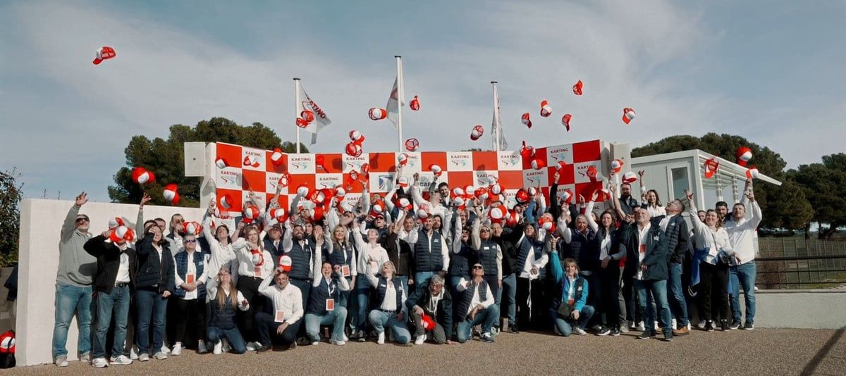 Photo de groupe au circuit de karting, casquettes lancées en l’air