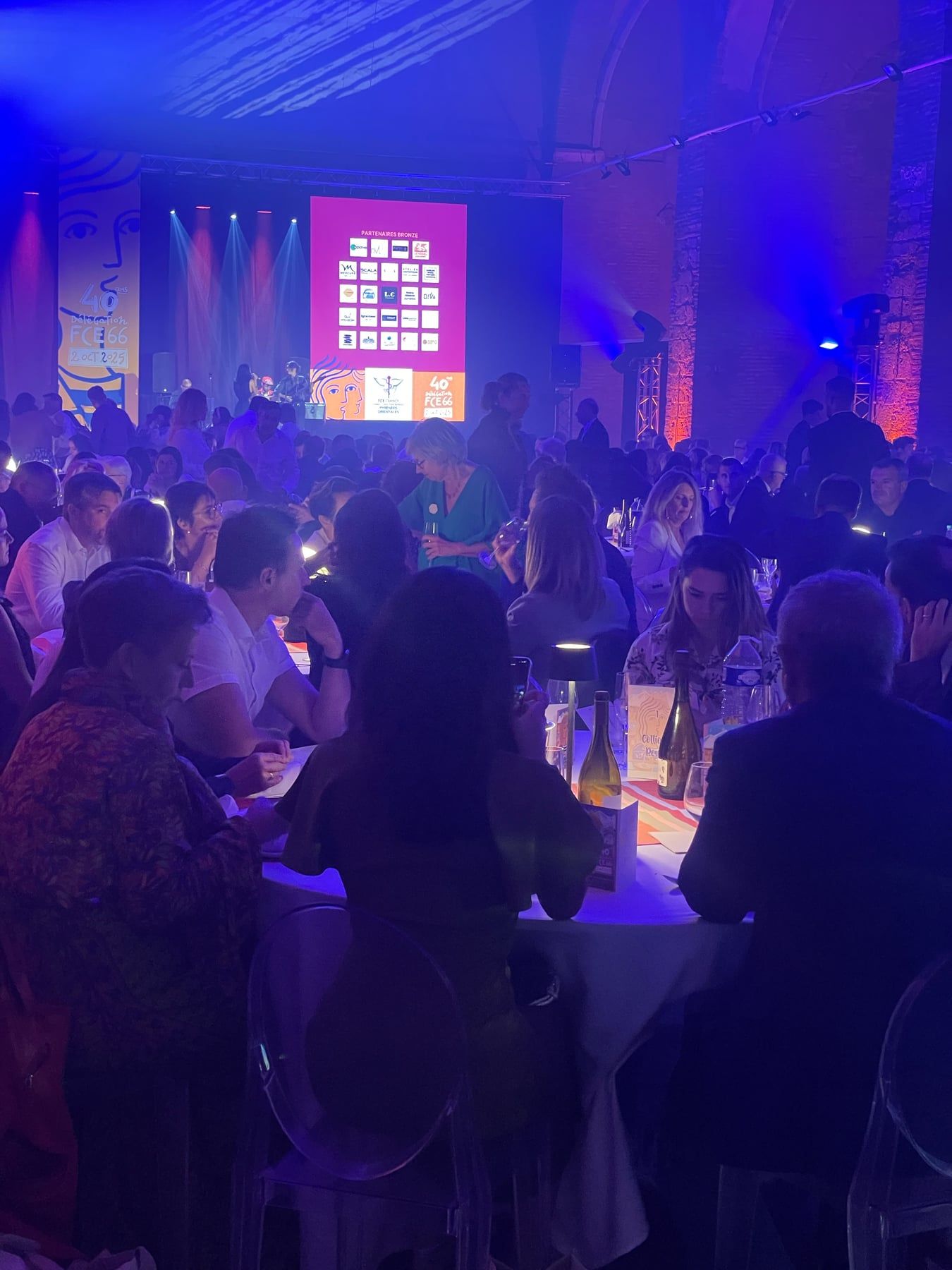 Soirée des 40 ans de FCE66, invités attablés devant l'écran des partenaires