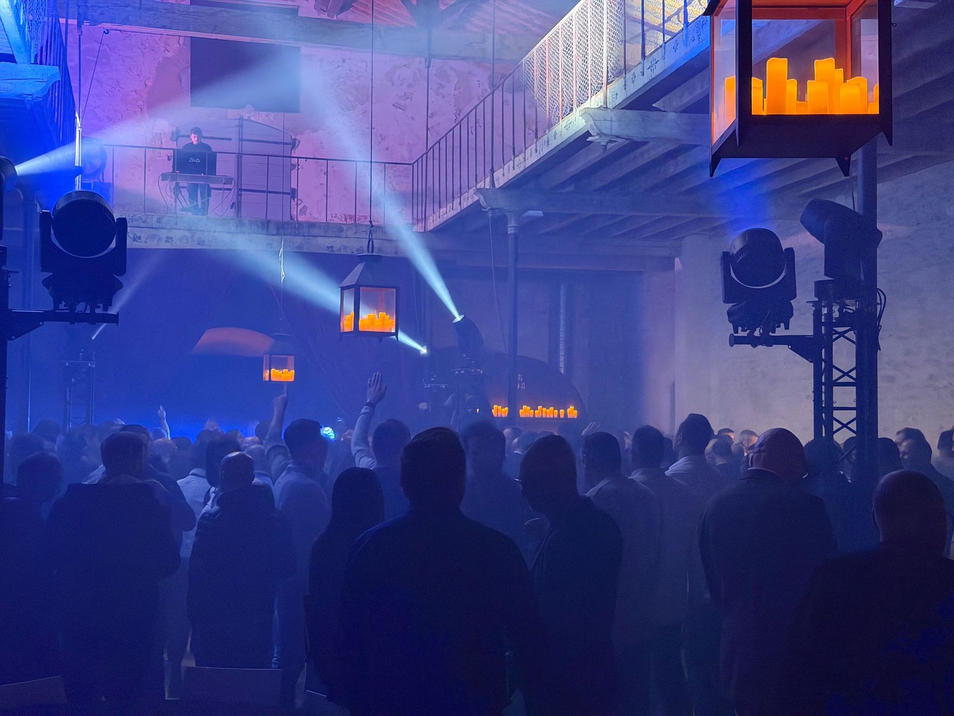 DJ sur une passerelle et invités sous les faisceaux lumineux lors de la soirée Tout Faire